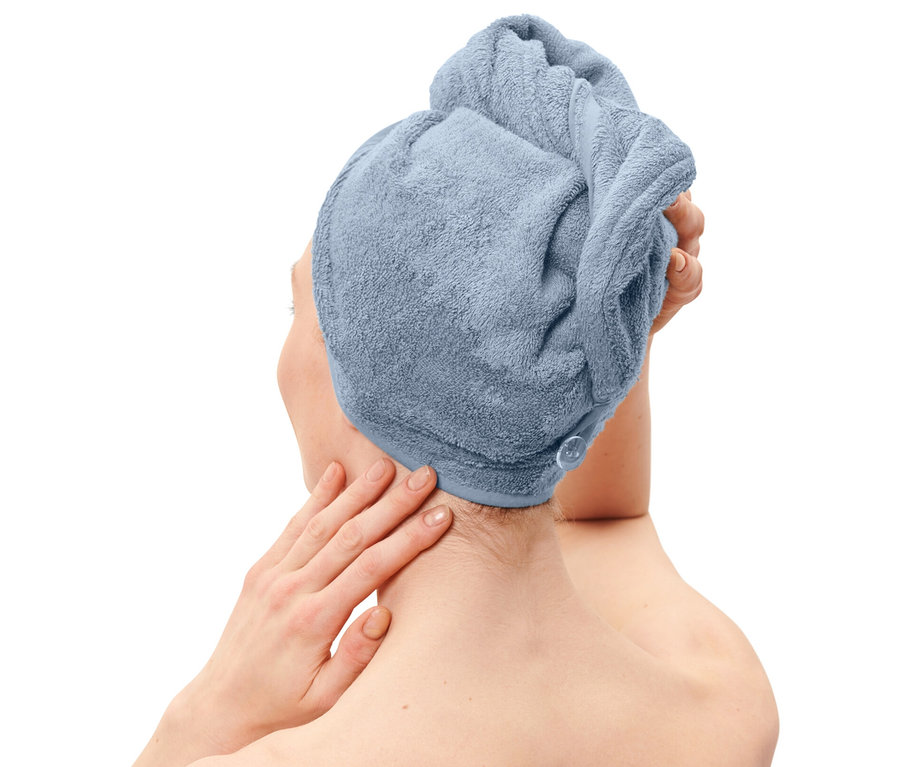 Frau mit Turban-Handtuch, hellblau, auf dem Kopf und Handtuch in der gleichen Farbe um den Körper gewickelt.