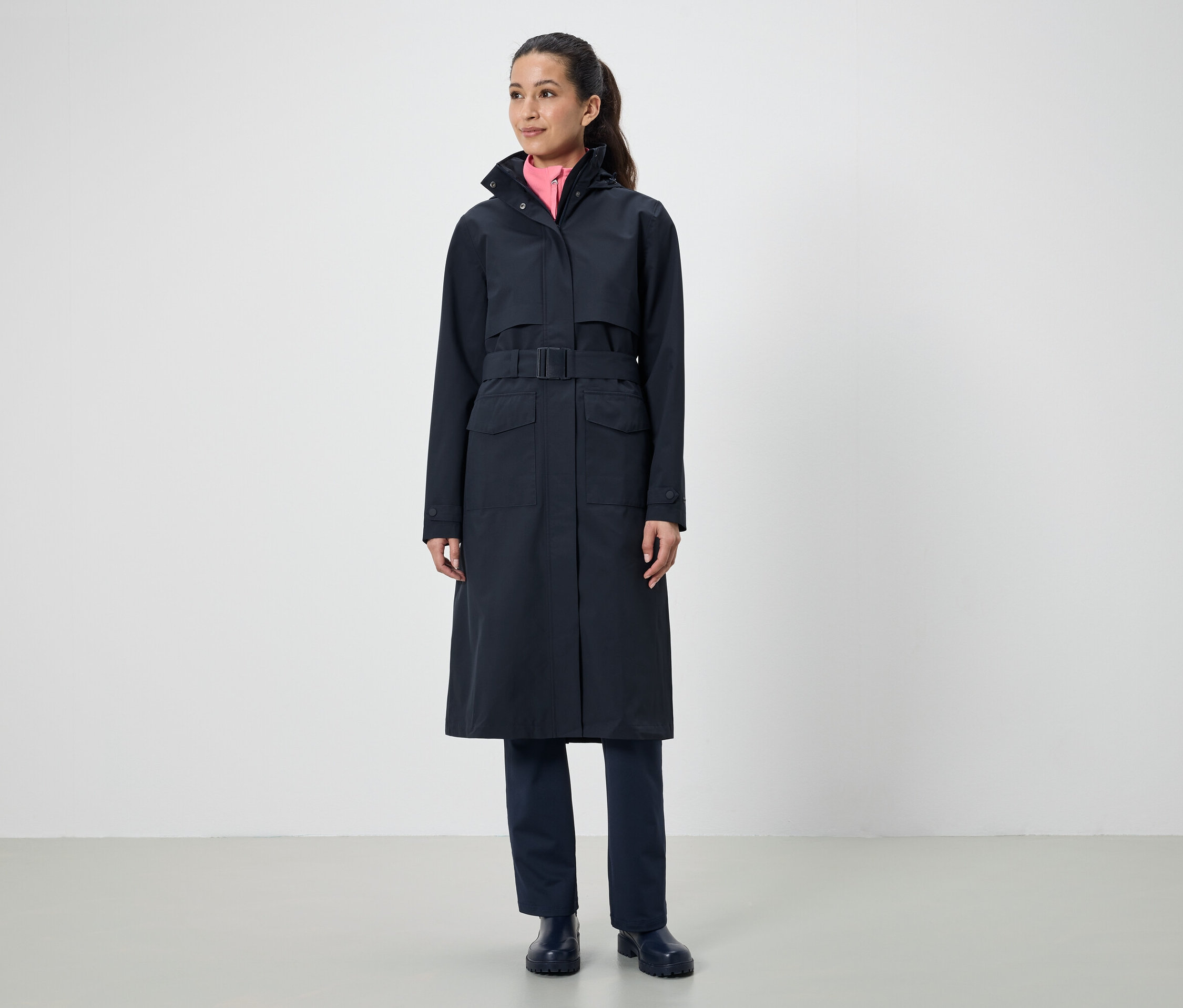 Eine Frau trägt einen langen, schwarzen Mantel mit Gürtel.