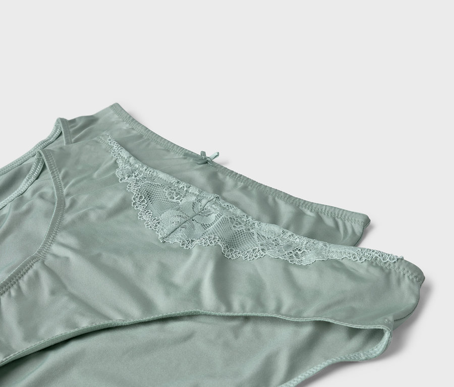 Zwei hellgrüne Damenslips mit Spitze liegen übereinander.