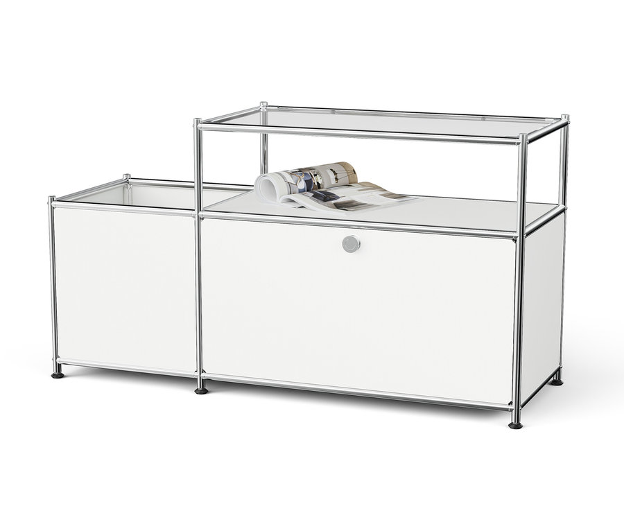 Weißes modulares Aufbewahrungssystem mit Chromrahmen und Glasböden, auf dem oberen Boden liegt eine zusammengerollte Zeitschrift.