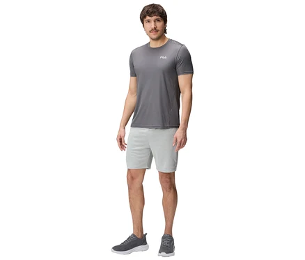 Mann in grauem T-Shirt, hellgrauen FILA Herren-Funktions-Sweatshorts und grauen Turnschuhen stehend.