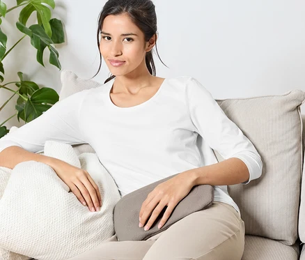 Eine Frau sitzt auf einem Sofa mit Kissen.
