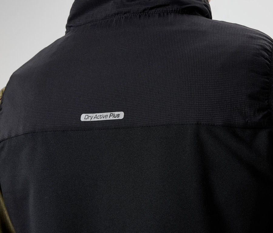 Nahaufnahme der Rückseite einer schwarzen Weste mit der Aufschrift "Dry Active Plus" über einem olivgrünen, langärmeligen Hemd.