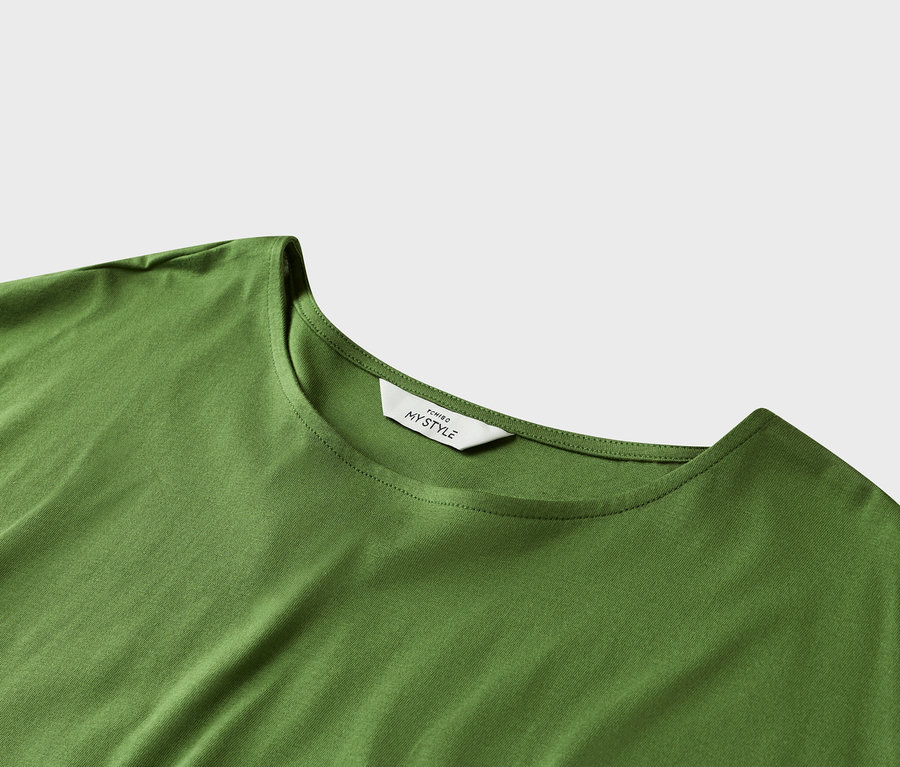 Nahaufnahme eines grünen T-Shirts mit einem weißen Etikett am Halsausschnitt.