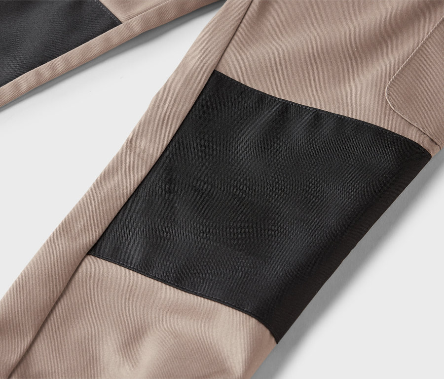 Nahaufnahme von beigen Hosen mit schwarzen Flicken.