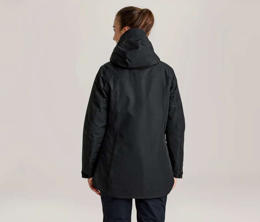 Frau von hinten, die eine schwarze Jacke mit Kapuze und dunkle Hosen trägt, die Haare sind hochgebunden.
