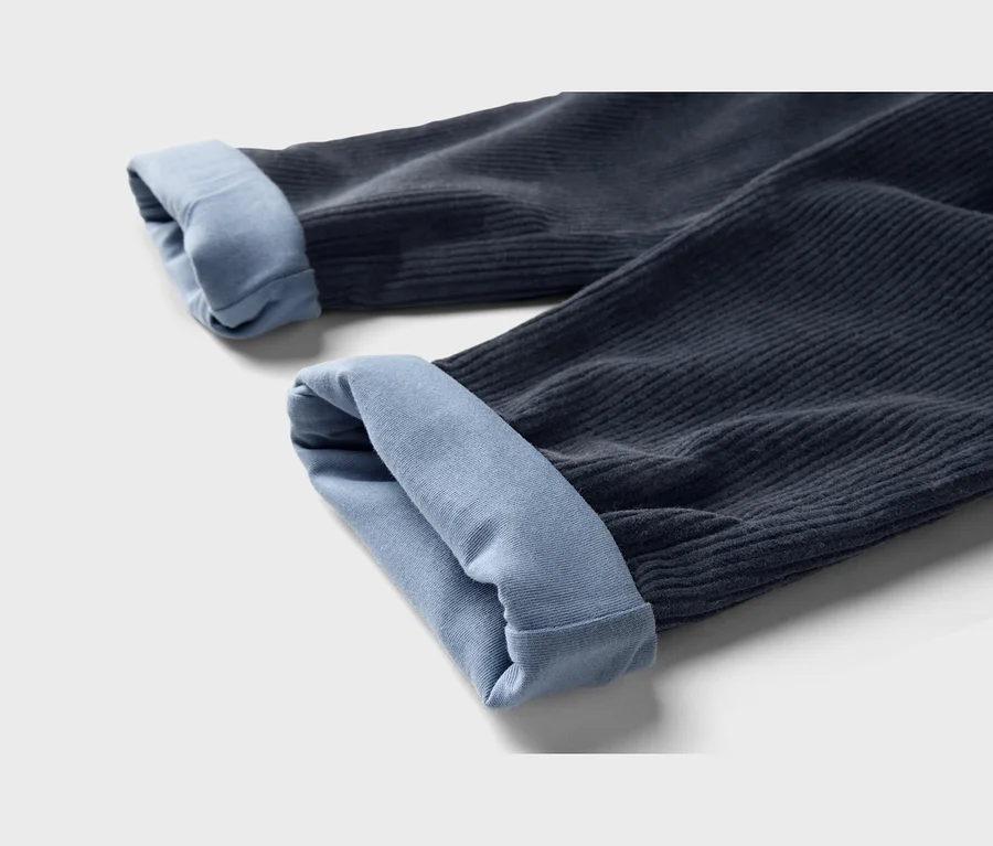 Zwei dunkelblaue Cordhosenbeine mit hellblauen, hochgekrempelten Bündchen.