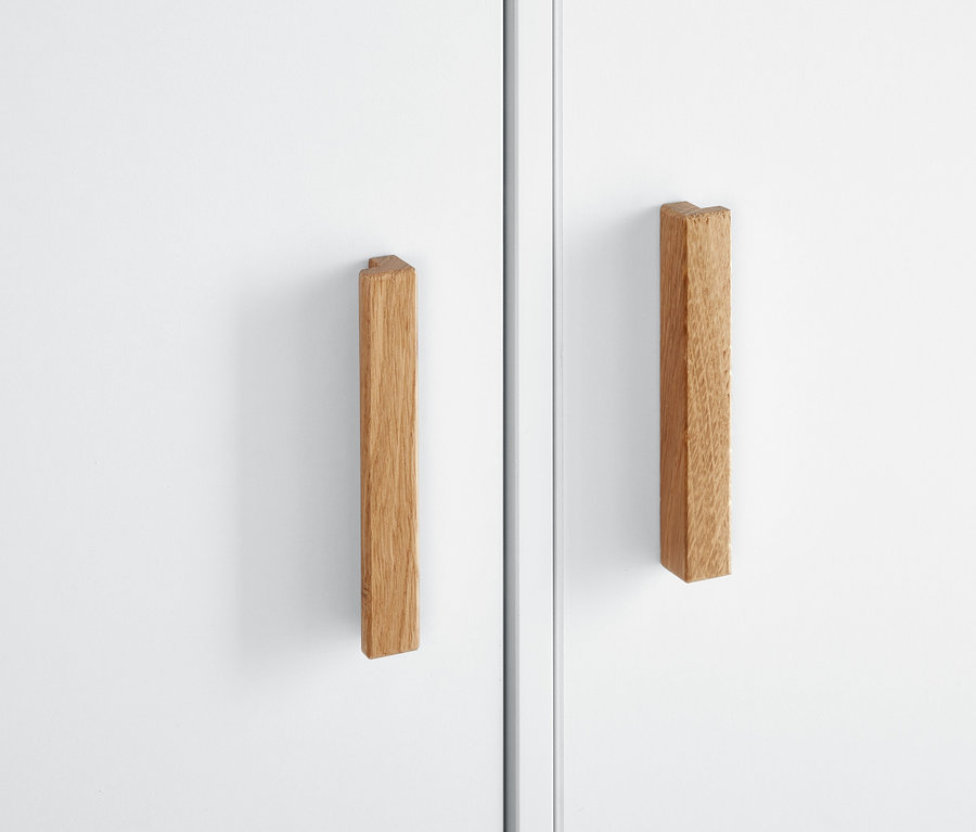 Detailansicht eines weißen Kleiderschranks mit Holzgriffen.