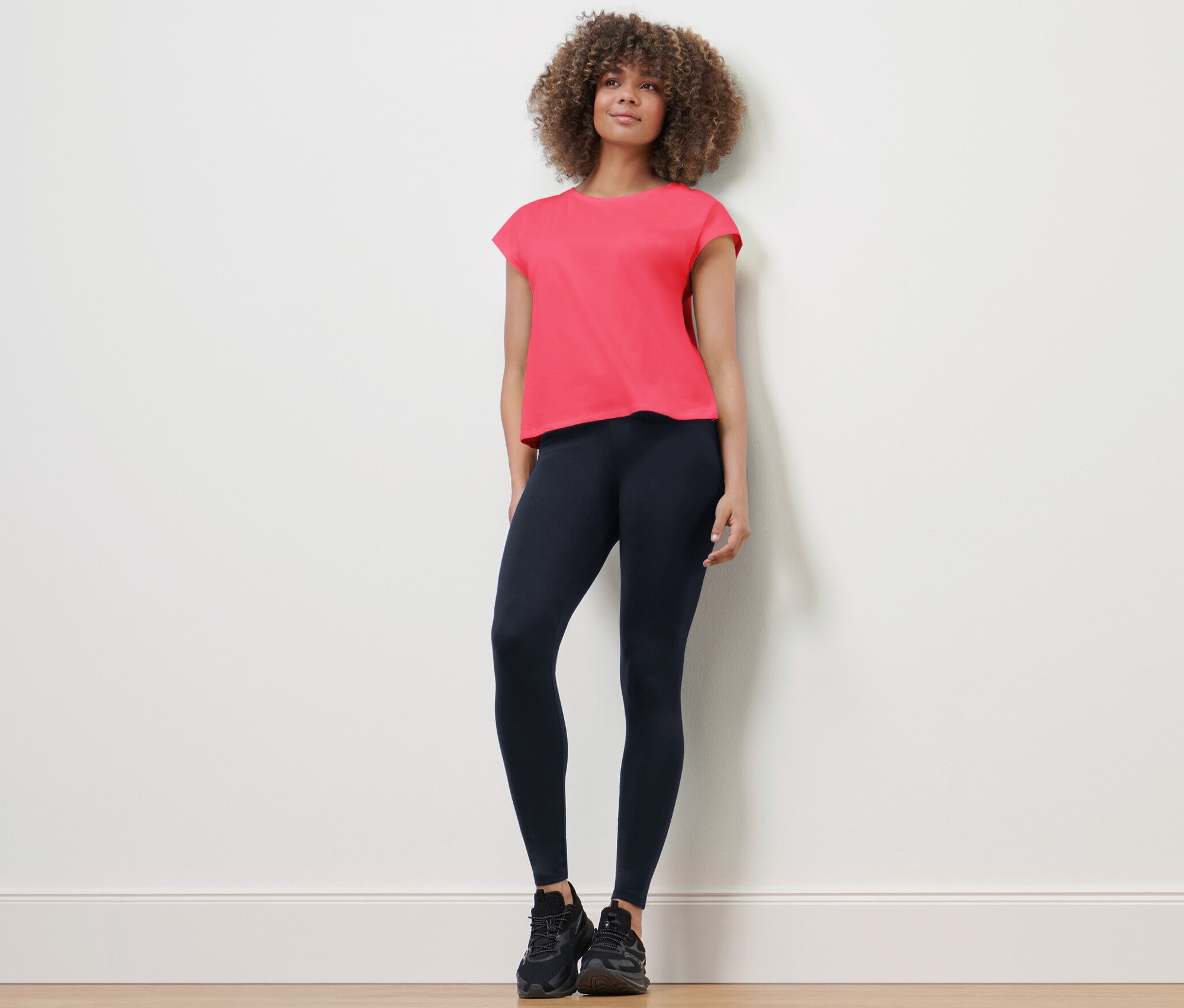 Frau steht und trägt eine Sporttight und ein T-Shirt.