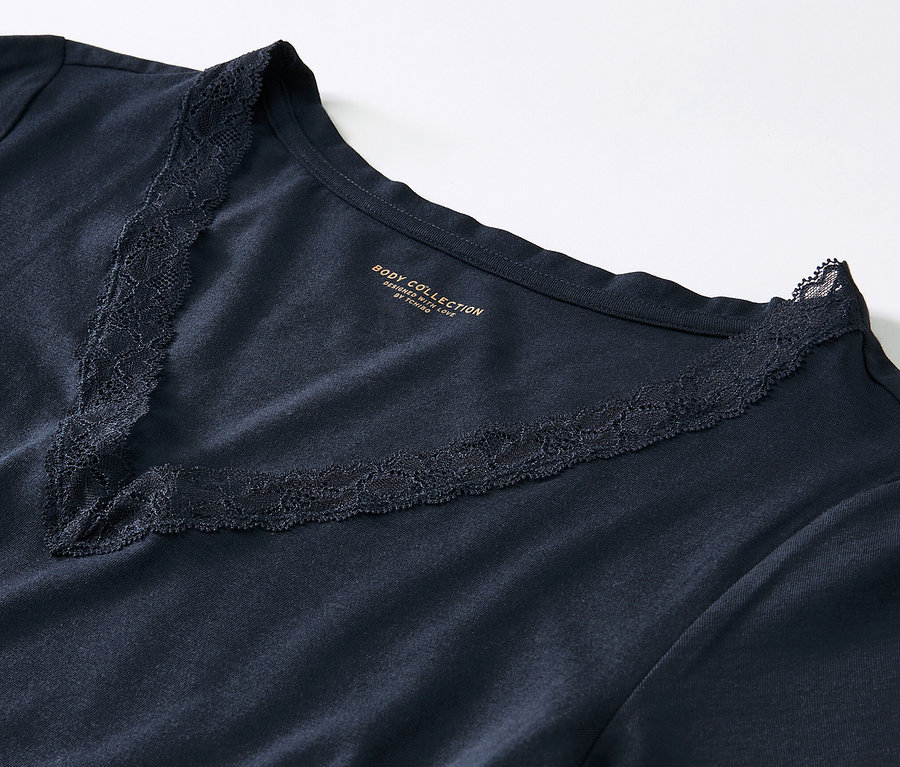 Detailansicht eines dunkelblauen Pyjamas mit Spitze am V-Ausschnitt.