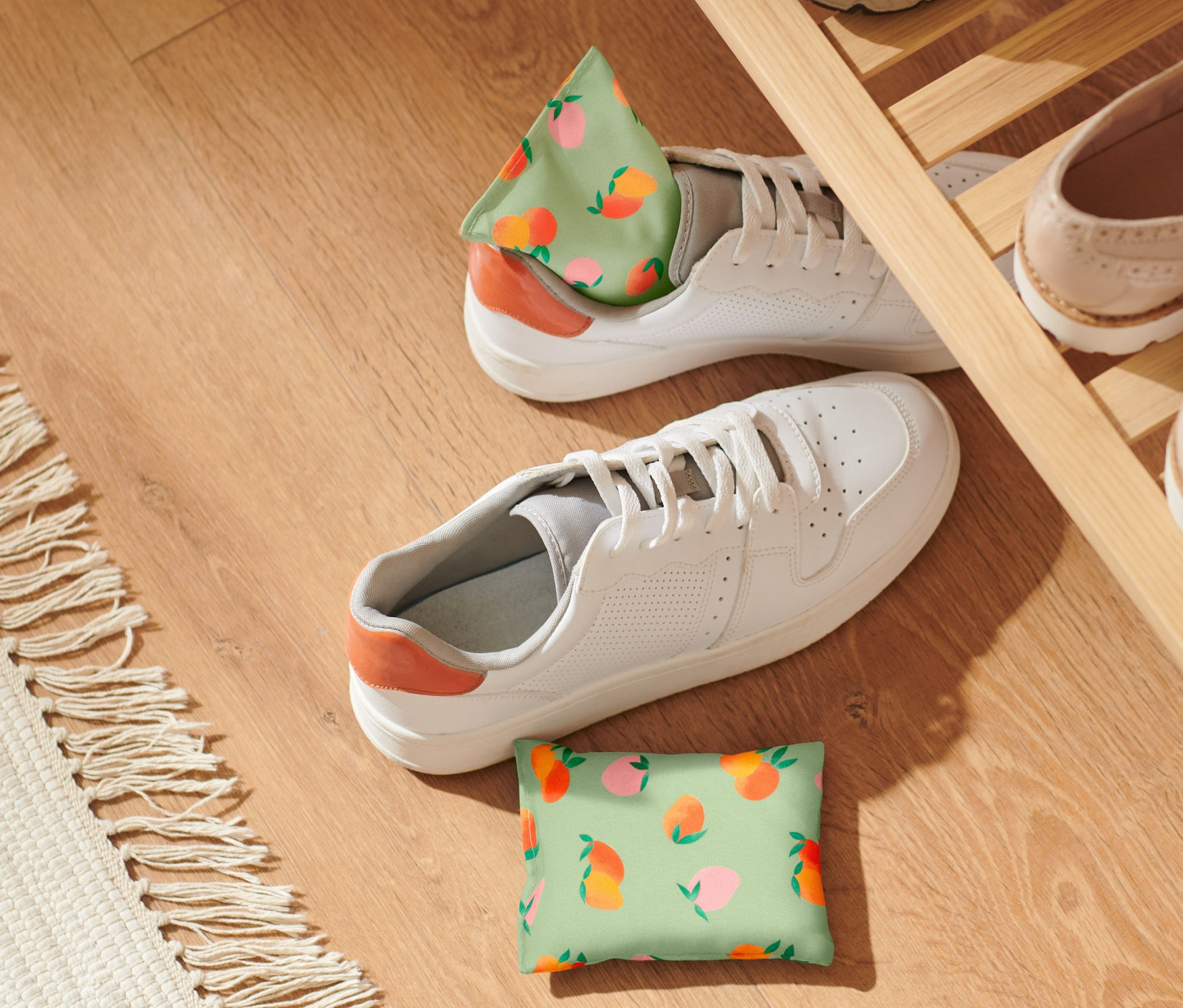 Zwei Erfrischungskissen mit Pfirsichmuster liegen neben weißen Schuhen auf einem Holzboden.
