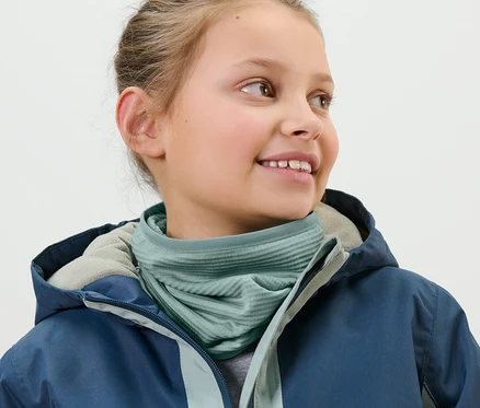 Mädchen trägt ein Kinder-Multifunktionstuch und eine blaue Jacke.