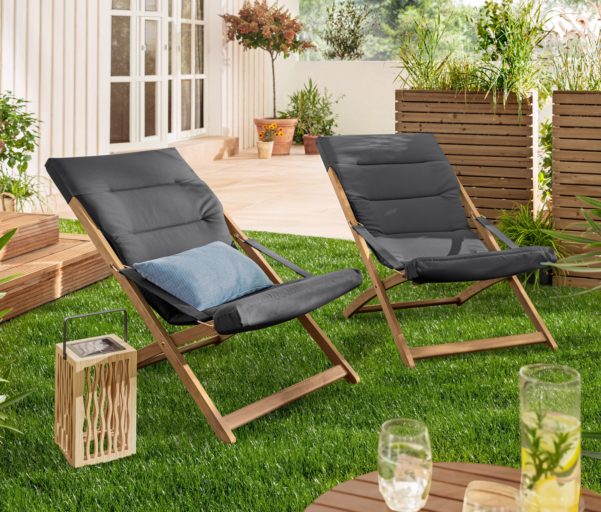 Auf Rasen stehen eine Solar-Laterne und zwei anthrazitfarbene Faltbarer Relax-Sessel.