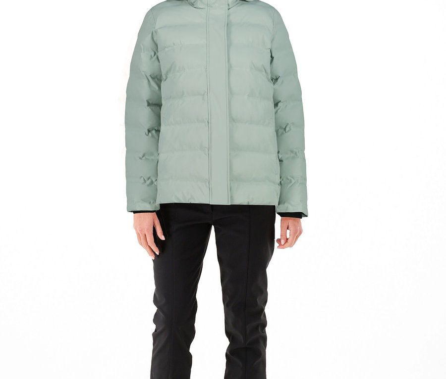 Frau trägt eine hellgrüne CMP Damen-Steppjacke mit Kapuze, schwarze Hose, schwarze Kappe und helle Stiefel.