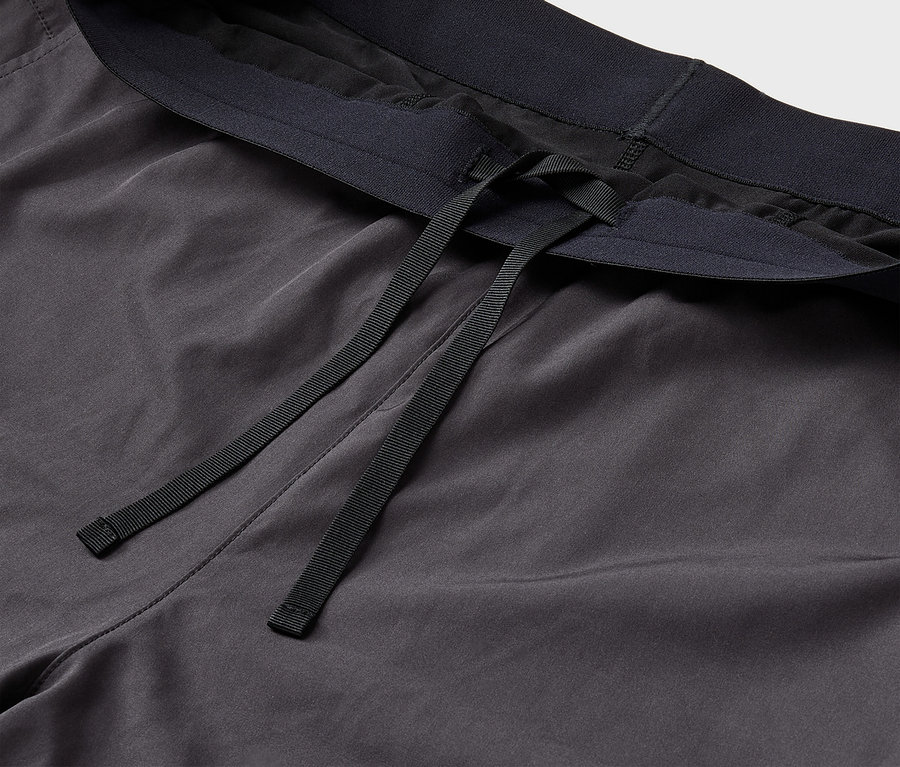 Detail einer grauen Trainingshose mit schwarzem Gummibund und Kordel.