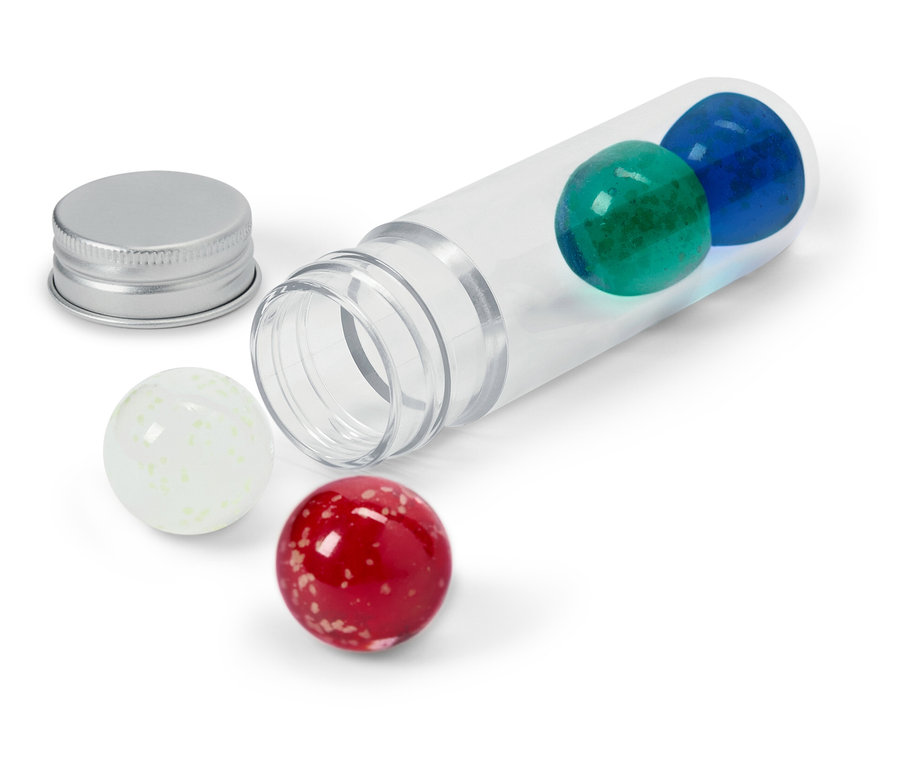 Eine durchsichtige Röhre liegt auf der Seite mit einer blauen und einer grünen Kugel darin, einem silbernen Deckel daneben und einer weißen und einer roten Kugel außerhalb.
