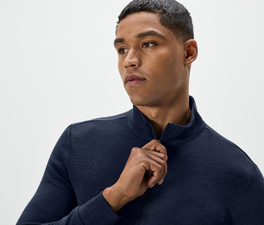 Mann öffnet dunkelblaue Trainingsjacke mit Reißverschluss.