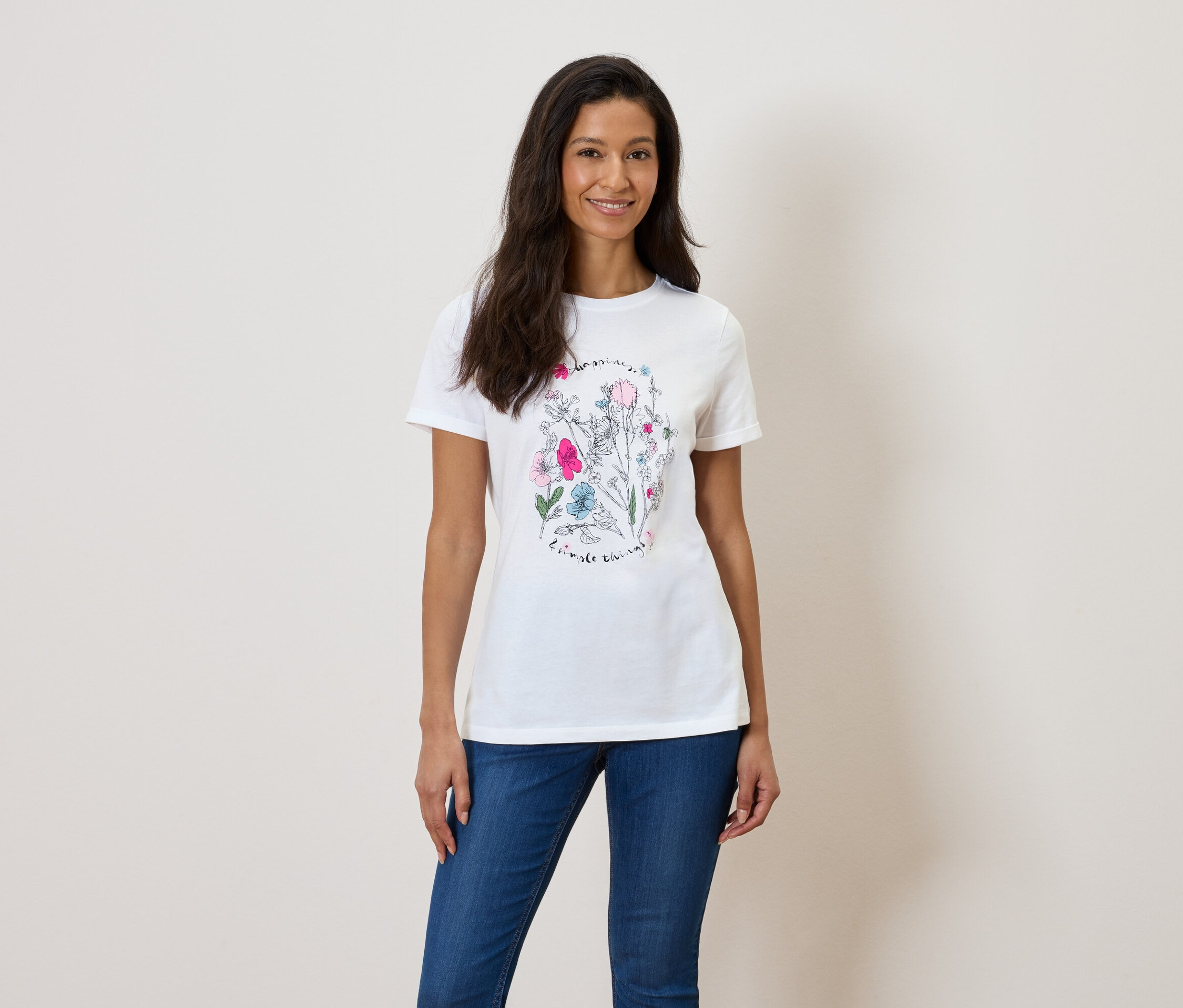 Frau trägt ein weißes T-Shirt mit Blumendruck und blaue Jeans.