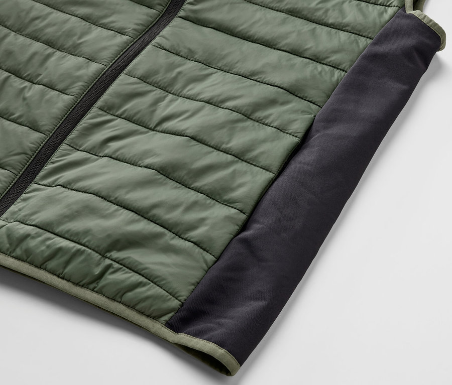 Detail einer grünen Steppweste »pack light« mit schwarzem Reißverschluss und Einsatz.