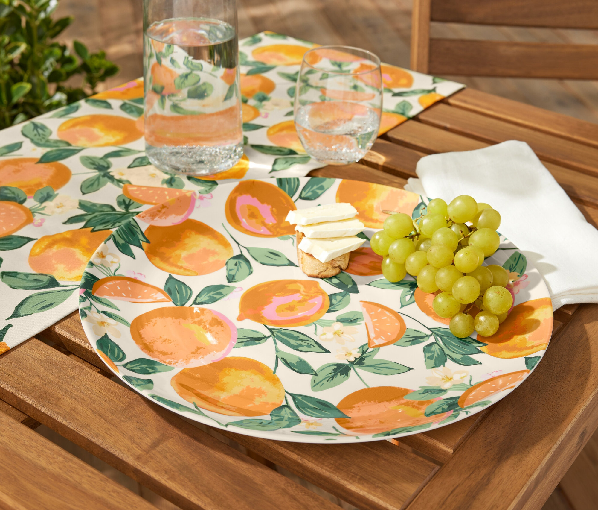 Servierteller mit Obst, Käse und Trauben auf einem Holztisch.