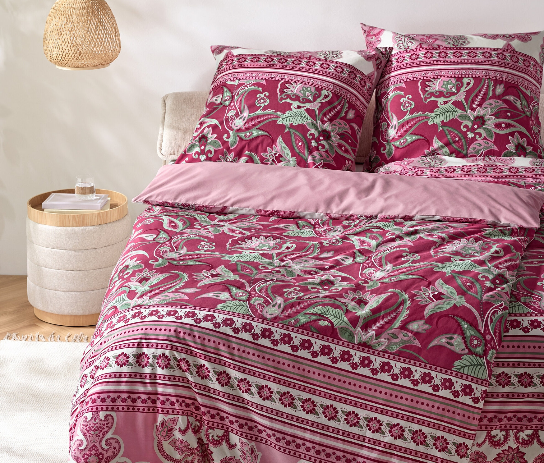 Ein Paisley-Bettwäsche-Set auf einem Bett mit Nachttisch und Lampe.