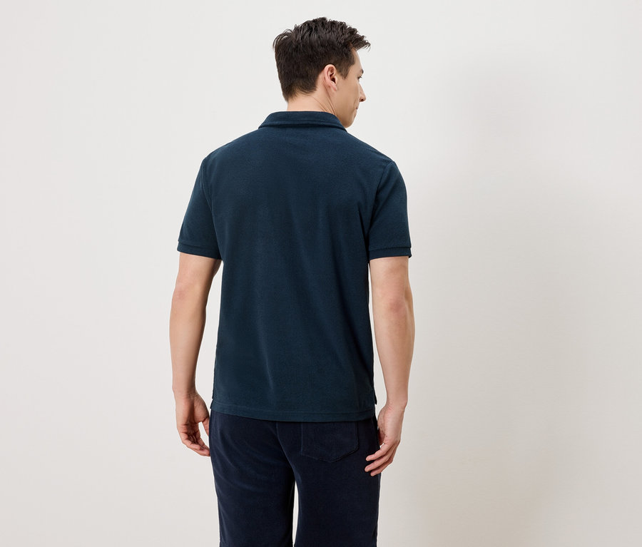 Rückansicht eines Mannes, der ein dunkelblaues Poloshirt und marineblaue Hosen trägt.
