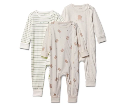 Drei Baby-Schlafanzüge stehen aufgereiht da: einer gestreift, einer mit Bärenmuster und einer einfarbig mit Bären-Applikation.