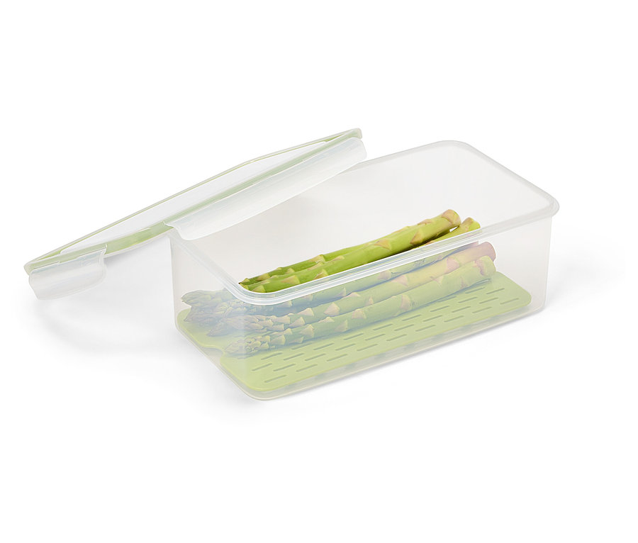 Einige Stangen grüner Spargel liegen in einer durchsichtigen Frischhaltedose mit einem grünen Einsatz und einem transparenten Deckel.