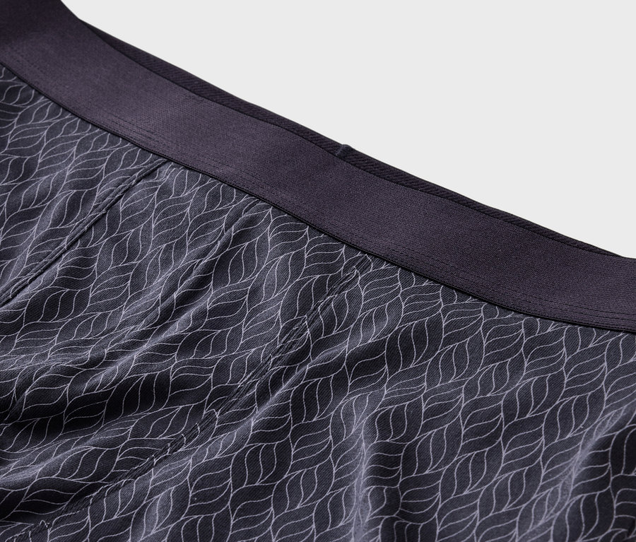 Nahaufnahme von dunkelgrauen Boxershorts mit weißem Blattmuster und dunkelgrauem Bund.