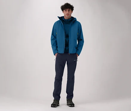 Mann in blauer Jacke und CMP Herren-Stretch-Nylon-Wanderhose. Er steht vor einem hellen Hintergrund.