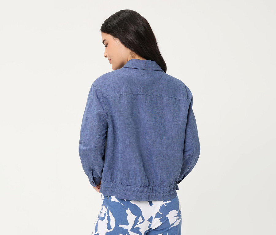 Frau von hinten, trägt eine blaue Olsen Jeansjacke und blau-weiß gemusterte Hose.