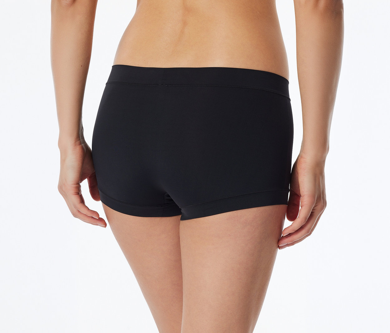 Rückenansicht einer Person in schwarzen Boxershorts, die Hände sind seitlich leicht sichtbar.