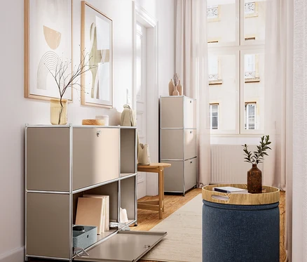 Heller Raum mit Holzboden. Links beiger modularer Schrank mit offenem Fach, Büchern und Deko. Rechts ein Hocker aus Massivholz und ein blauer Pouf mit Holztablett und Pflanze.