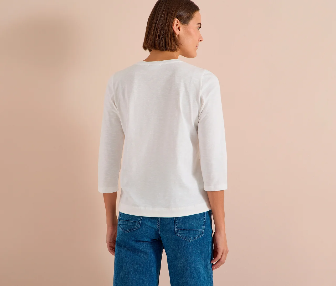 Frau von hinten, die ein weißes CECIL 3/4- Shirt und blaue Jeans trägt.