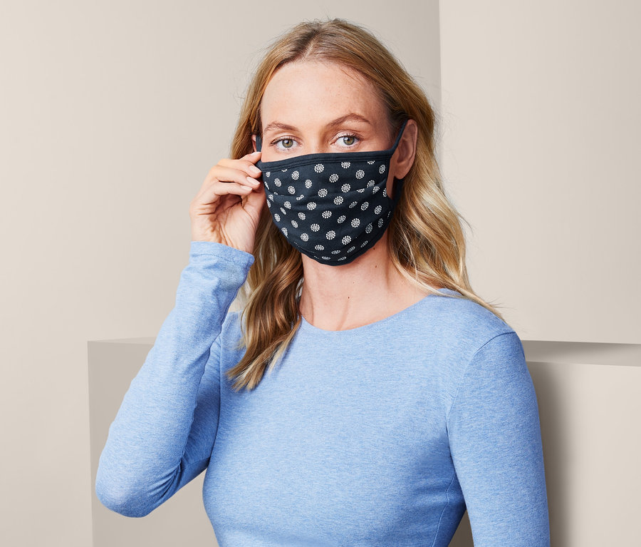 Frau setzt eine Community-Masken-Set mit einem schwarz-weißen Muster auf.
