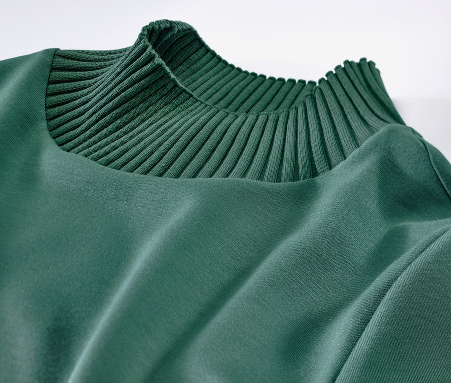 Detailaufnahme eines grünen Sweatshirts mit Stehkragen.