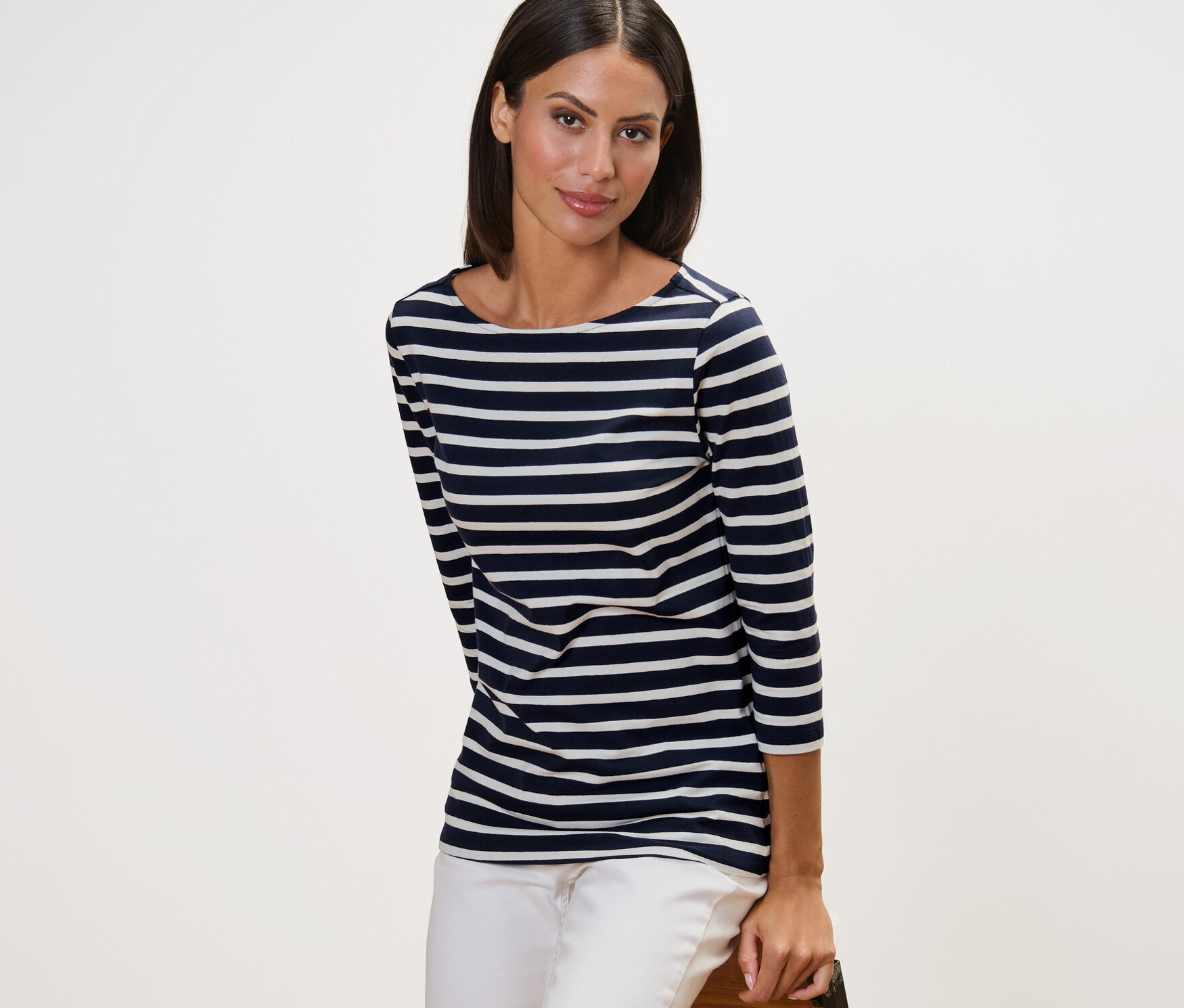 Frau posiert in einem navy gestreiften Shirt mit 3/4-Arm und weissen Hosen.