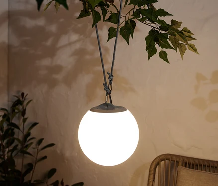 Eine LED-Akku-Pendelleuchte hängt an einem Ast.