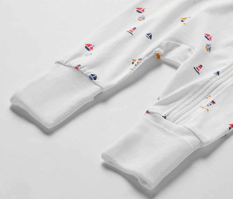 Detailaufnahme eines weißen Baby-Schlafanzugs mit maritimem Muster.