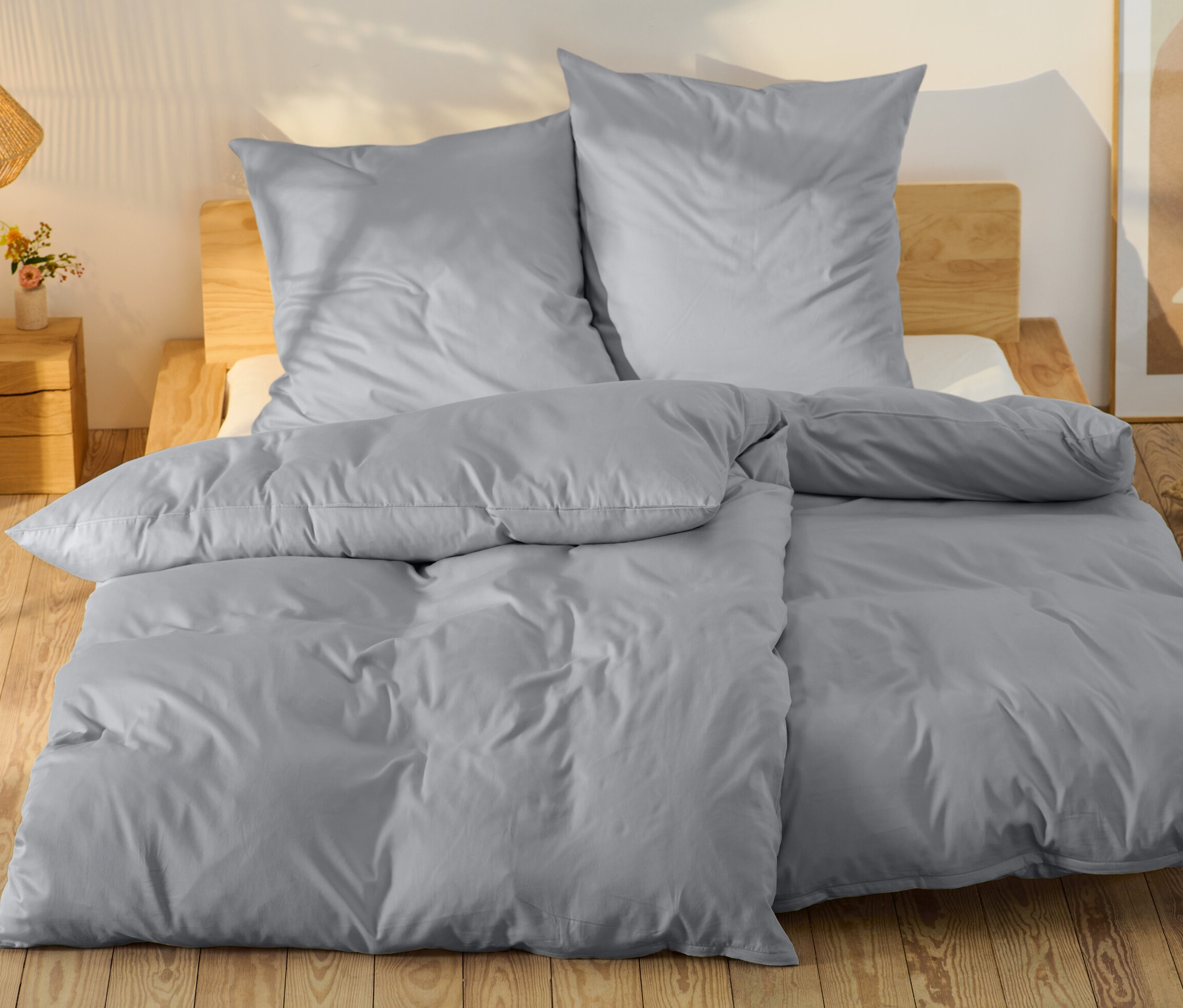 Graue Baumwollsatin-Bettwäsche in Normalgröße und Übergröße auf einem Bett.