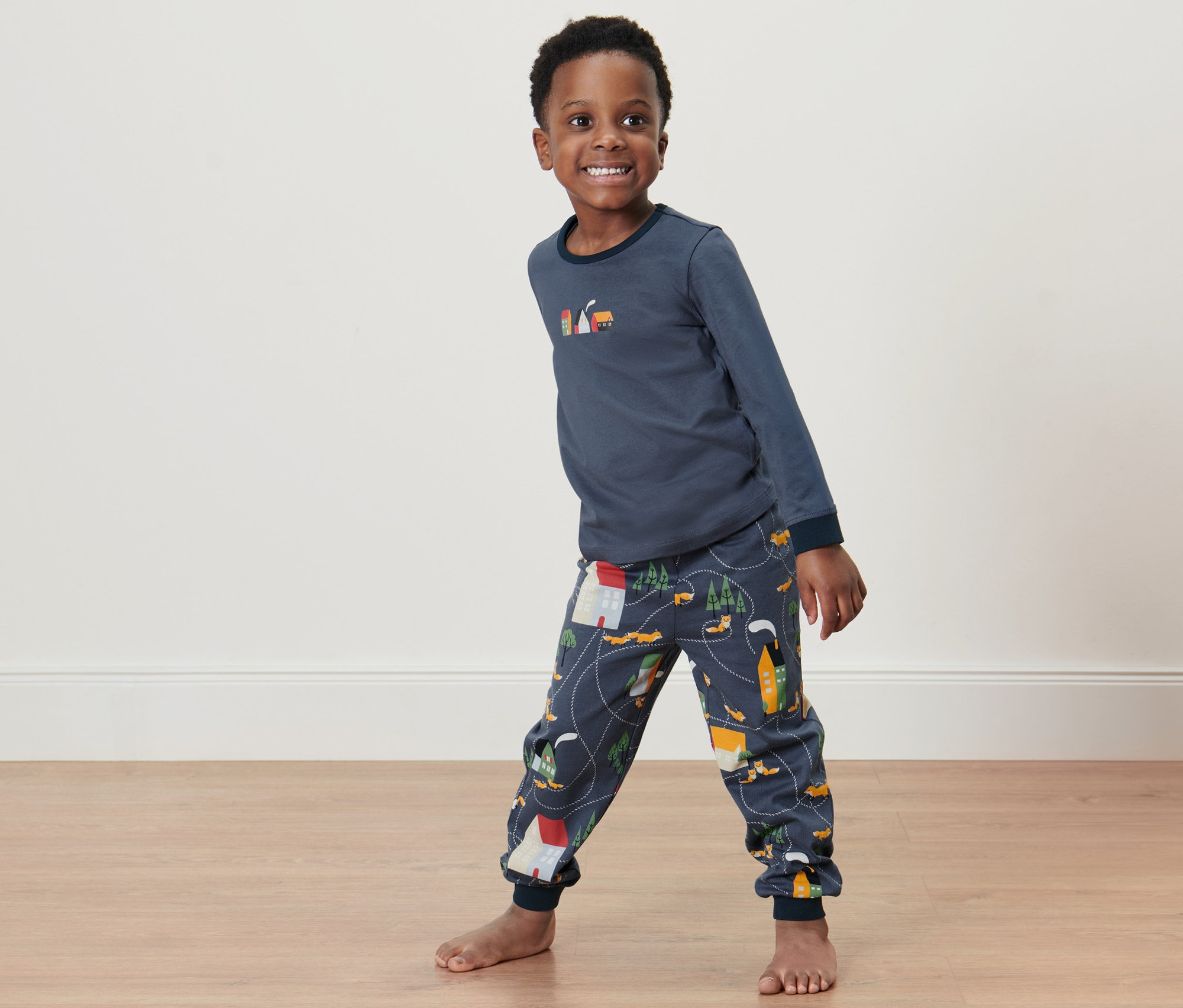 Ein lächelnder Junge posiert in einem 2 Kleinkind-Pyjamas.