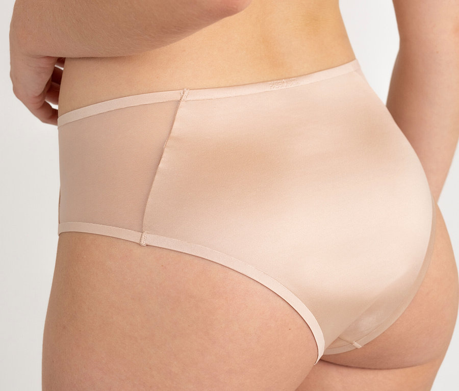 Rückansicht einer Frau, die beigefarbene Slips mit transparenten Einsätzen trägt.