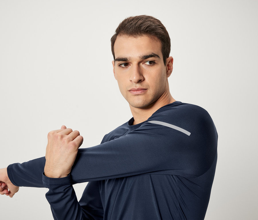 Mann dehnt Arm in dunkelblauem Sport-Langarmshirt.