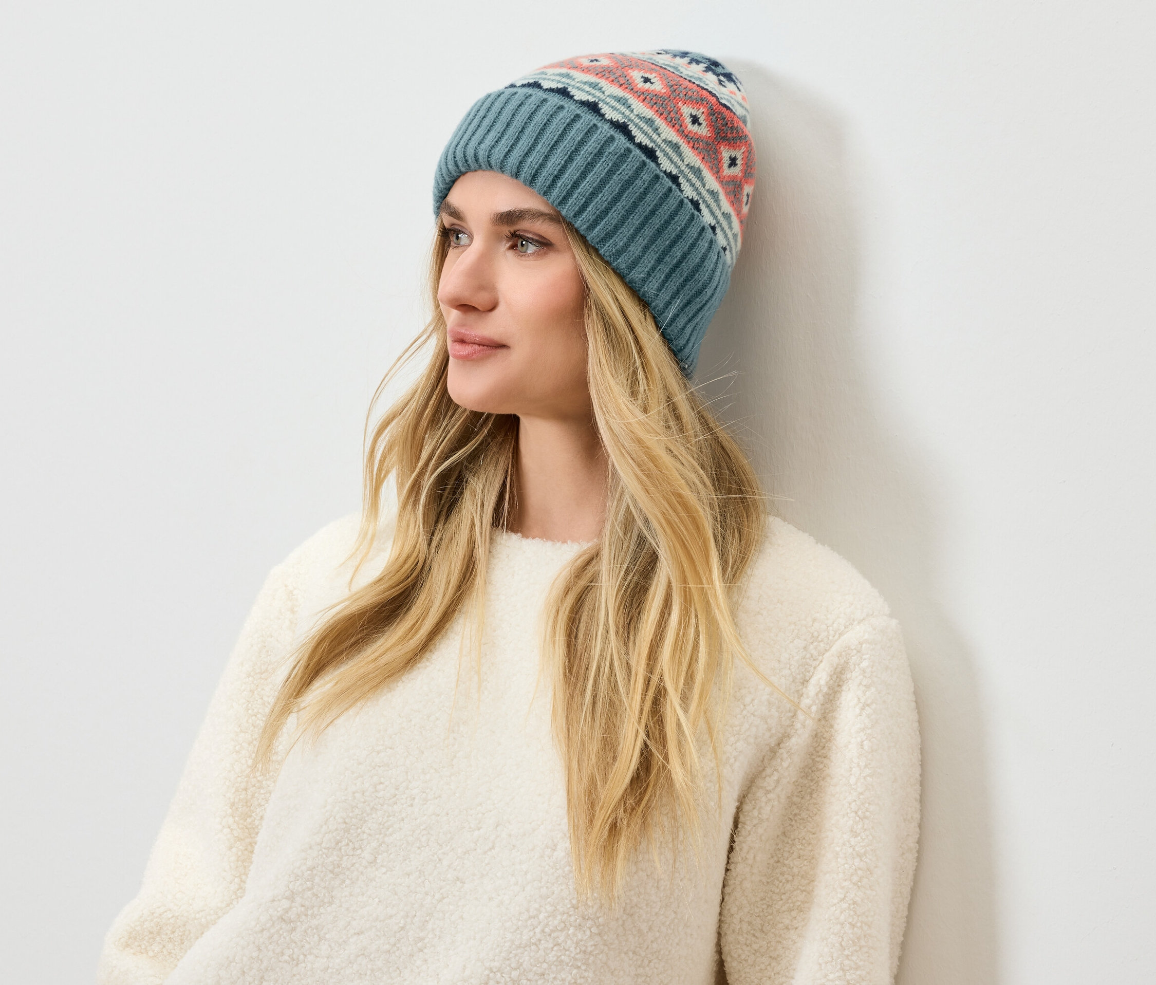 Frau mit langen blonden Haaren und einer gemusterten, blauen Mütze.