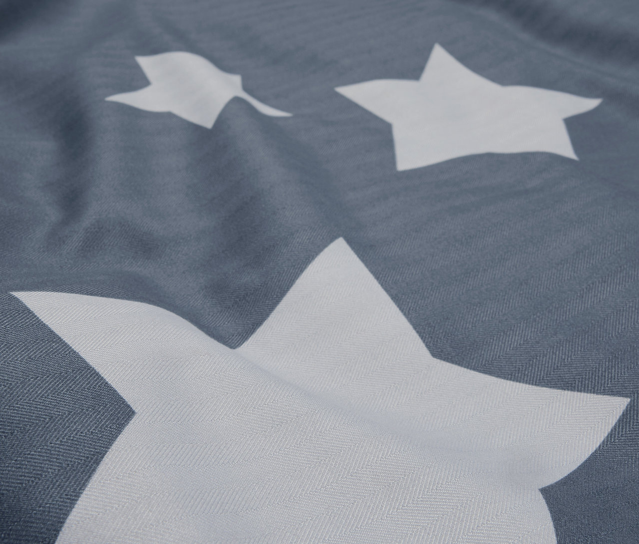 Detailaufnahme eines grauen Stoffes mit weißen Sternen.