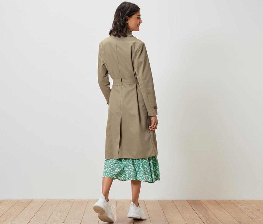 Frau von hinten in einem sandfarbenen Trenchcoat.