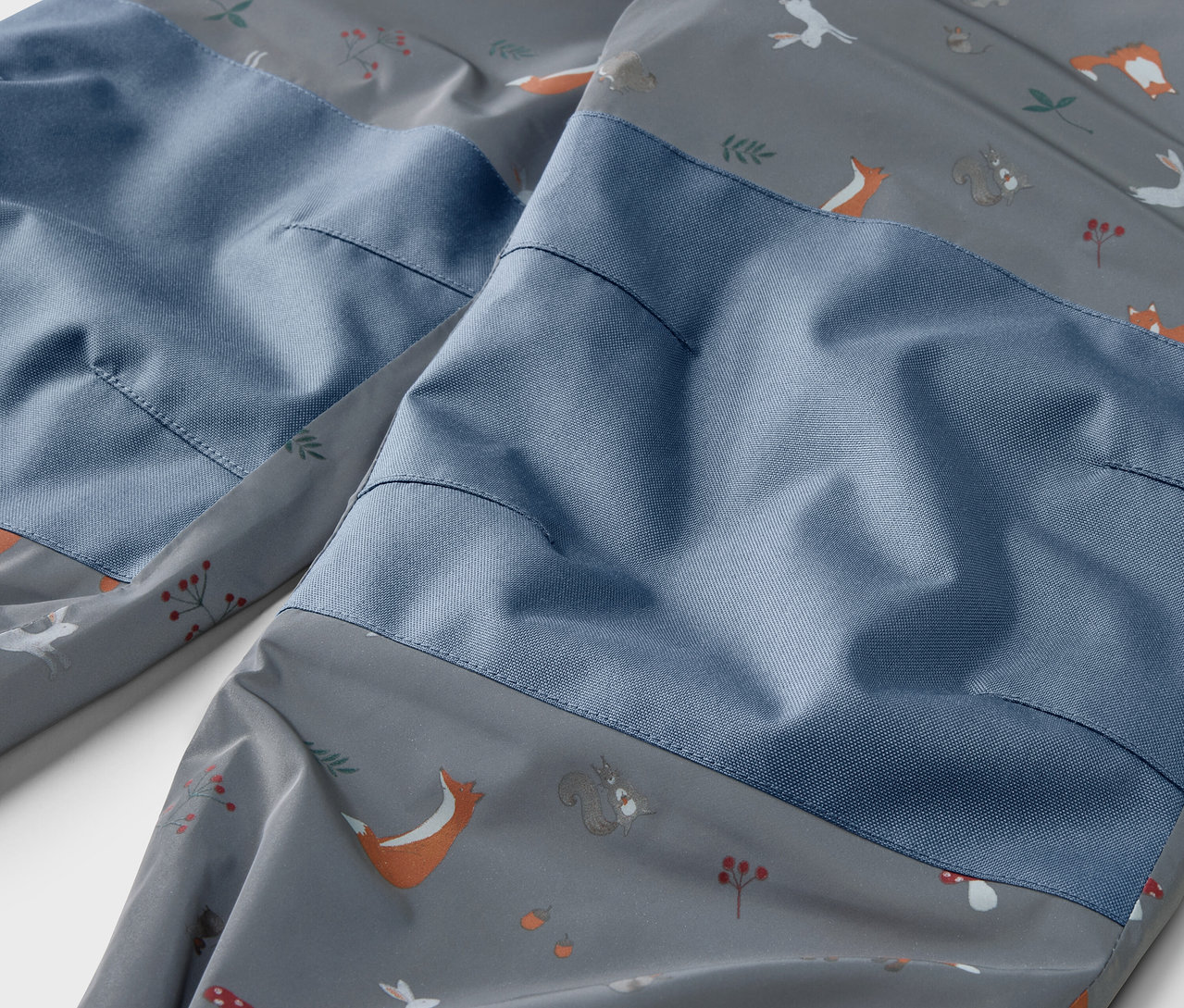 Detailaufnahme einer Kinder-Thermo-Regenhose mit reflektierenden Designelementen und Tiermuster.