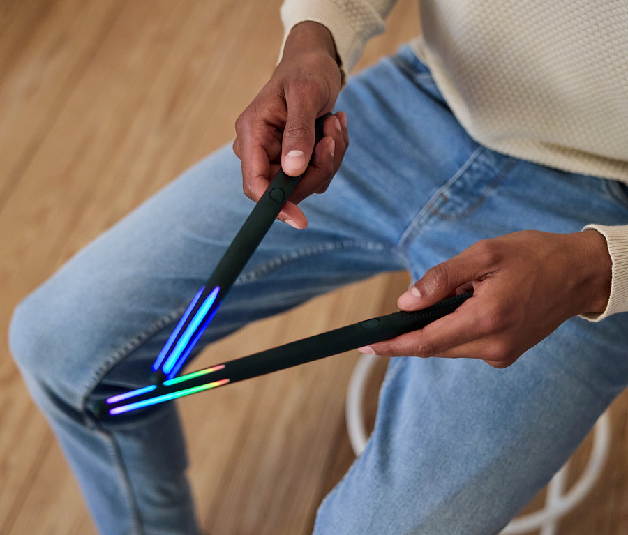 Mann hält zwei schwarze Stäbe mit Lichtern an den Enden.