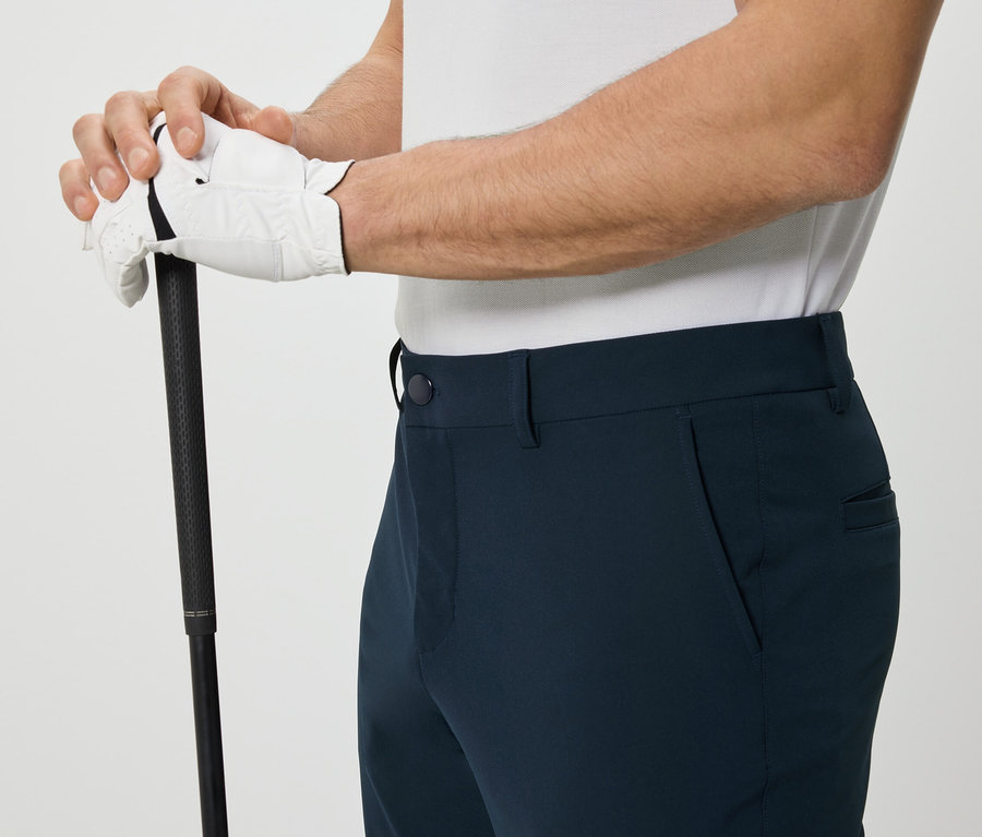 Mann hält Golfschläger und trägt eine Outdoorhose.