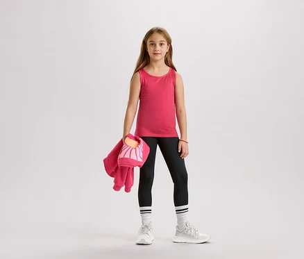 Mädchen mit rosa Tanktop, schwarzen Leggings, weißen Socken und Turnschuhen, hält eine rosa Jacke und eine Tasche.